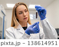 Laboratory technician analyzing blood sample contained in a glass test tube at a clinical workstation. 138614951
