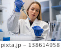 Laboratory technician using a micropipette to transfer colored liquid into microcentrifuge tubes at a clean research station. 138614958