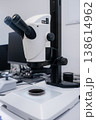 Advanced digital microscope positioned over a glass slide containing biological specimen at research workstation. 138614962