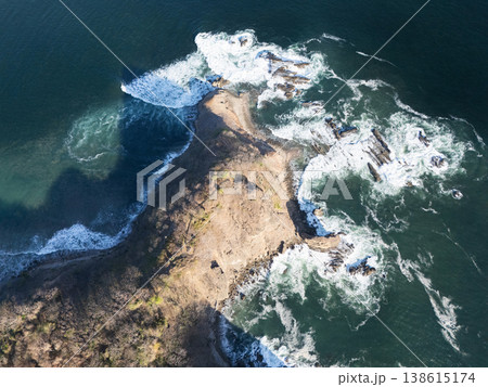 Aerial view shows a rocky coastal area with waves crashing on the shore Aerial view shows a rocky coastal area with waves crashing on the shore 138615174