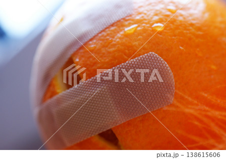 dissected damaged cut orange stuck with a plaster and dressing 138615606