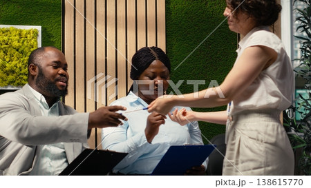 Candidates in a hallway receiving registration forms from office secretary, participating in the recruitment process and waiting to start professional job interview. Filling in documents. 138615770