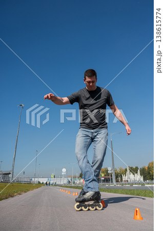 A Caucasian man rollerblades around the slalom course. A Caucasian man rollerblades around the slalom course. 138615774
