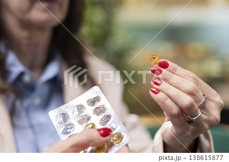 Close up of woman at home holding pills and vial of supplements as part of her daily care routine. Elderly female pensioner taking prescribed probiotics, balance and prevention. Close up of woman at home holding pills and vial of supplements as part of her daily care routine. Elderly female pensioner taking prescribed probiotics, balance and prevention. 138615877