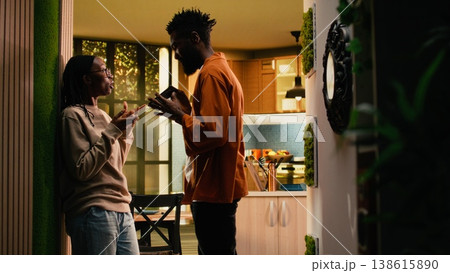 Black boyfriend seeing her girlfriend laugh at mobile phone screen, being suspicious about a potential affair, worrying about infidelity and dishonesty. Controlling toxic man in rage, bullying. 138615890