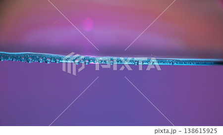 Air bubbles along a blue water surface with purple pink gradient background, clean liquid texture, macro underwater line, freshness concept. 138615925