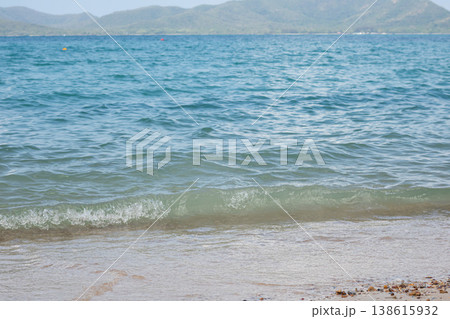 A soft green-blue wave curls along a sandy shore with pebbles, while distant hills fade into the horizon, offering a serene seaside atmosphere perfect for leisure and coastal travel themes. A soft green-blue wave curls along a sandy shore with pebbles, while distant hills fade into the horizon, offering a serene seaside atmosphere perfect for leisure and coastal travel themes. 138615932