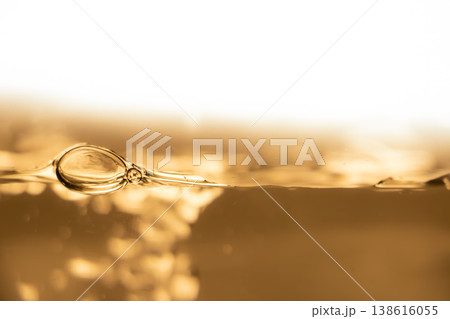 Golden liquid surface with bubble and ripples, abstract beverage background, warm light, macro waterline, luxury drink concept. Golden liquid surface with bubble and ripples, abstract beverage background, warm light, macro waterline, luxury drink concept. 138616055