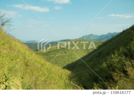 Green mountain valley with rolling hills under blue sky, peaceful natural landscape background with travel and wilderness concept. 138616177