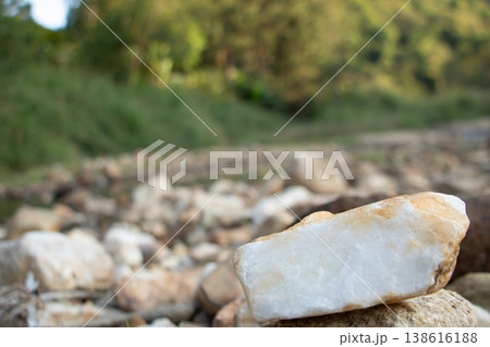 White stone in sharp focus among river rocks with soft green nature background, natural texture and geology concept. White stone in sharp focus among river rocks with soft green nature background, natural texture and geology concept. 138616188