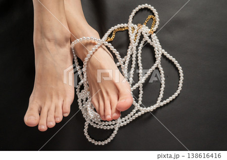 Foot fetish. Bare female feet with pearl beads. 138616416