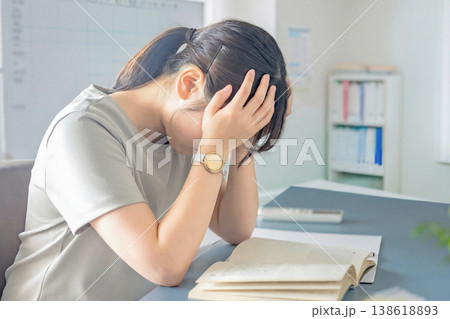 両手で頭を押さえて悩んでいるカット 138618893