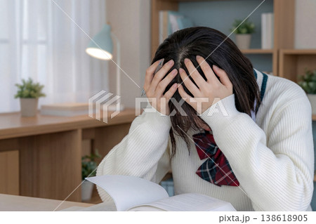 制服姿の女子生徒が机で頭を抱えているカット 制服姿の女子生徒が机で頭を抱えているカット 138618905