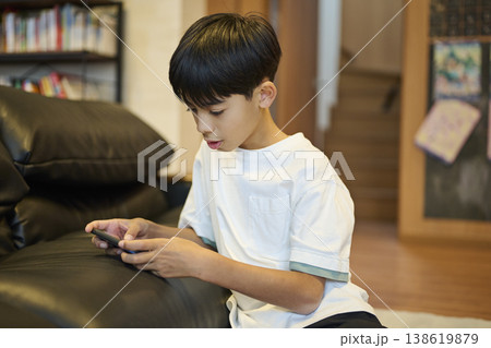 ソファに座りスマホを見つめる男の子 138619879