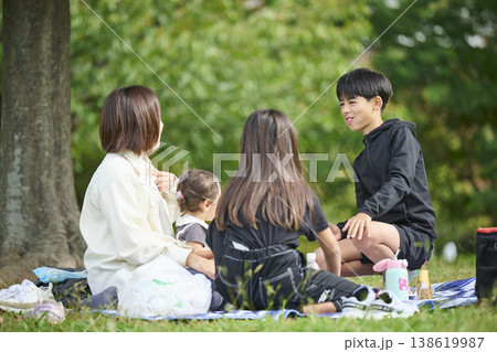 公園の木陰でくつろぐ母と子供たち 138619987