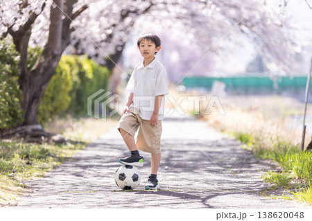 桜の下でサッカーボールを蹴る男の子 138620048