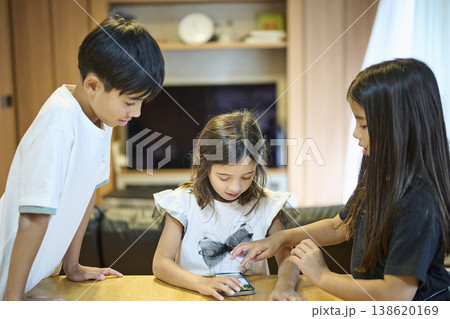 スマホを一緒に見る三兄妹 138620169