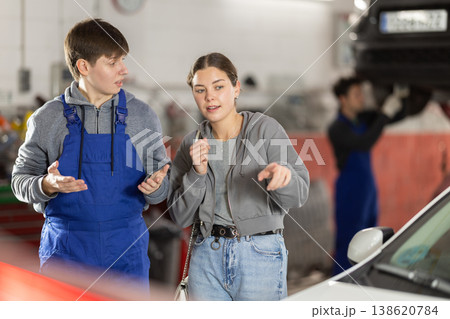 Male mechanic advises woman client on repairing of car in car service station Male mechanic advises woman client on repairing of car in car service station 138620784