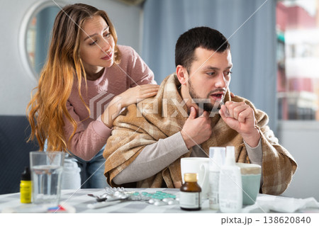 Man with cold symptoms sitting at home while girlfriend caring him 138620840