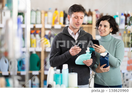 Man with wife uses barcode to get information about glass cleaner spray in mobile application. Man with wife uses barcode to get information about glass cleaner spray in mobile application. 138620960