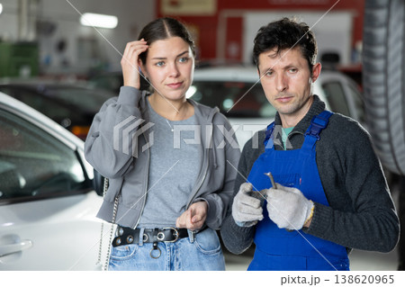 Man car mechanic talks with girl client in workshop and takes order. Man car mechanic talks with girl client in workshop and takes order. 138620965