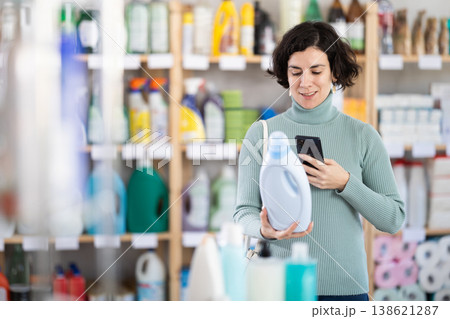 Middle-aged woman scanning QR-code on detergent at supermarket Middle-aged woman scanning QR-code on detergent at supermarket 138621287