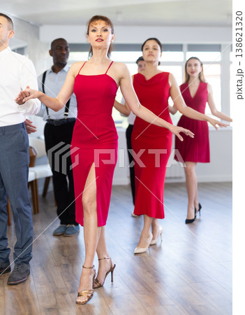 Woman in elegant red dress dancing waltz with partner during group class Woman in elegant red dress dancing waltz with partner during group class 138621320