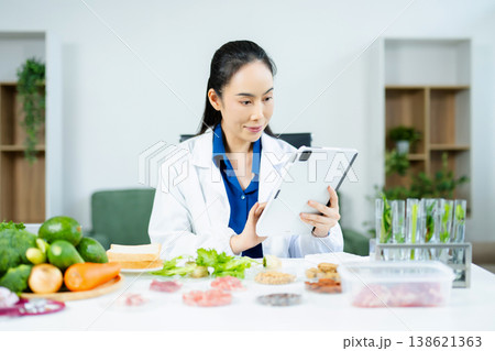 Professional nutritionist reviewing fresh vegetables and supplements for diet planning, health care, and wellness in a clinical nutrition setting 138621363