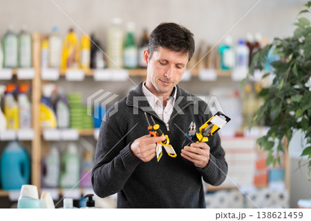 Male client in store inspects set of hand tools. Buyer selects necessary items for minor repairs 138621459