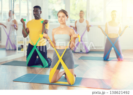 Girl exercising with elastic band during group fitness class 138621492