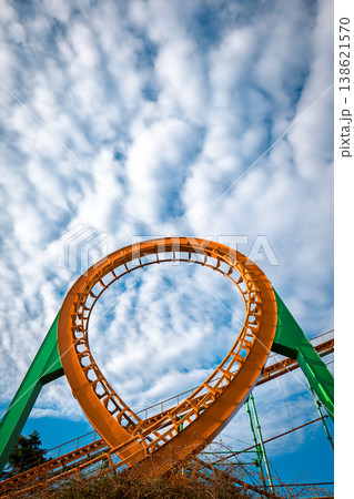 Central composition of a circular roller coaster loop against a dense pattern of white clouds 138621570