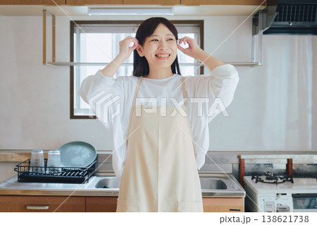 キッチンで微笑むエプロン姿の女性 家事や料理のイメージ ポジティブな生活シーン キッチンで微笑むエプロン姿の女性 家事や料理のイメージ ポジティブな生活シーン 138621738