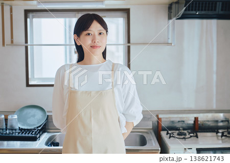 キッチンで微笑むエプロン姿の女性 家事や料理のイメージ ポジティブな生活シーン キッチンで微笑むエプロン姿の女性 家事や料理のイメージ ポジティブな生活シーン 138621743