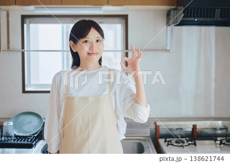 キッチンで微笑むエプロン姿の女性 家事や料理のイメージ ポジティブな生活シーン キッチンで微笑むエプロン姿の女性 家事や料理のイメージ ポジティブな生活シーン 138621744