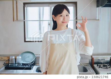 キッチンで微笑むエプロン姿の女性 家事や料理のイメージ ポジティブな生活シーン キッチンで微笑むエプロン姿の女性 家事や料理のイメージ ポジティブな生活シーン 138621746