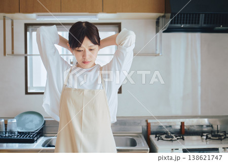 キッチンで微笑むエプロン姿の女性 家事や料理のイメージ ポジティブな生活シーン 138621747