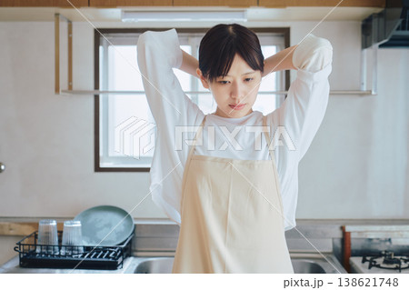 キッチンで微笑むエプロン姿の女性 家事や料理のイメージ ポジティブな生活シーン キッチンで微笑むエプロン姿の女性 家事や料理のイメージ ポジティブな生活シーン 138621748