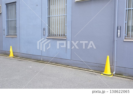 建物の壁面に並ぶ黄色いカラーコーンと駐停車禁止の看板 138622065