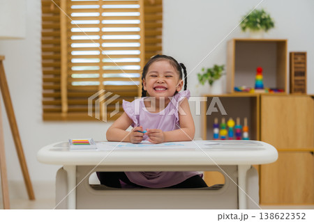 happy preschool child girl drawing and painting with colorful oil pastels on paper 138622352