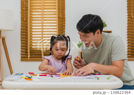 Caption/Description: father and child girl drawing and painting with colorful oil pastels on paper 138622364