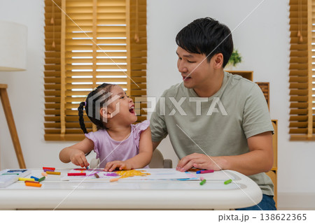cheerful father and child girl drawing and painting with colorful oil pastels on paper 138622365