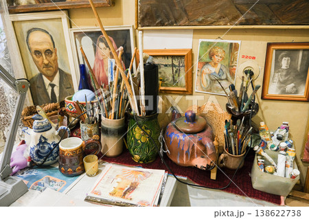 A table with a variety of art supplies, including paintbrushes, cups, and vases 138622738