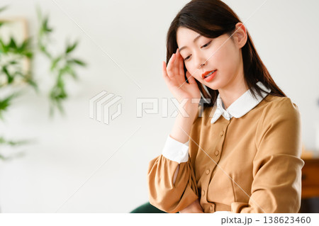女性が頭痛で手をこめかみに当てる 138623460