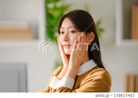 女性が頬に手を当ててスキンケアする様子 138623483