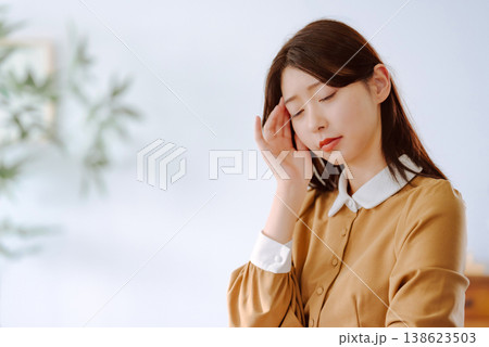 女性が頭痛で手をこめかみに当てる 138623503