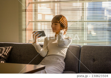 女性がソファでスマホを操作する 女性がソファでスマホを操作する 138623504