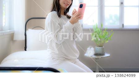 ベッドでスマートフォンを見る女性 ベッドでスマートフォンを見る女性 138624099