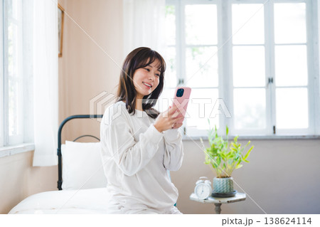 ベッドでスマートフォンを見る女性 ベッドでスマートフォンを見る女性 138624114