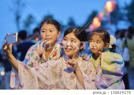 夕暮れの夏祭りでピースサインの母と姉妹 夕暮れの夏祭りでピースサインの母と姉妹 138624179