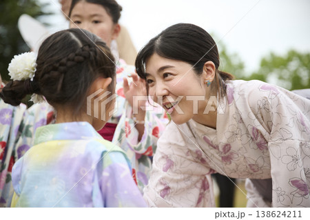 浴衣姿の母親と娘が笑顔で向き合う夏祭り 138624211